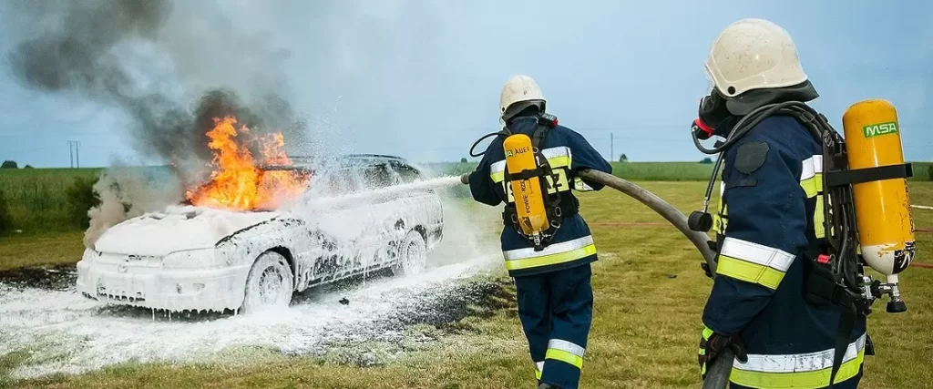 Bomberos apagando un auto con destrucción total por incendio
